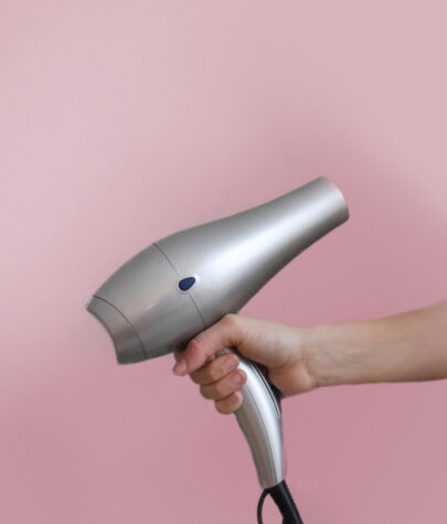Guest at The Laundry Rooms holding a hair dryer in front of a pink wall